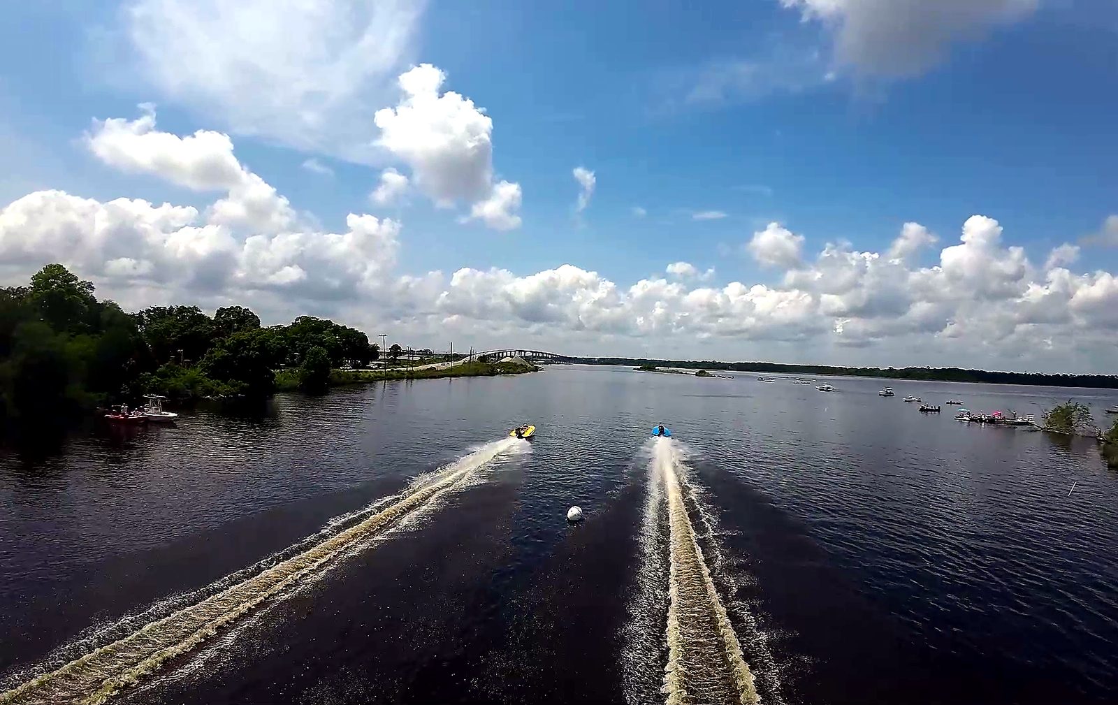 Two drag boats charging up the river between green banks
