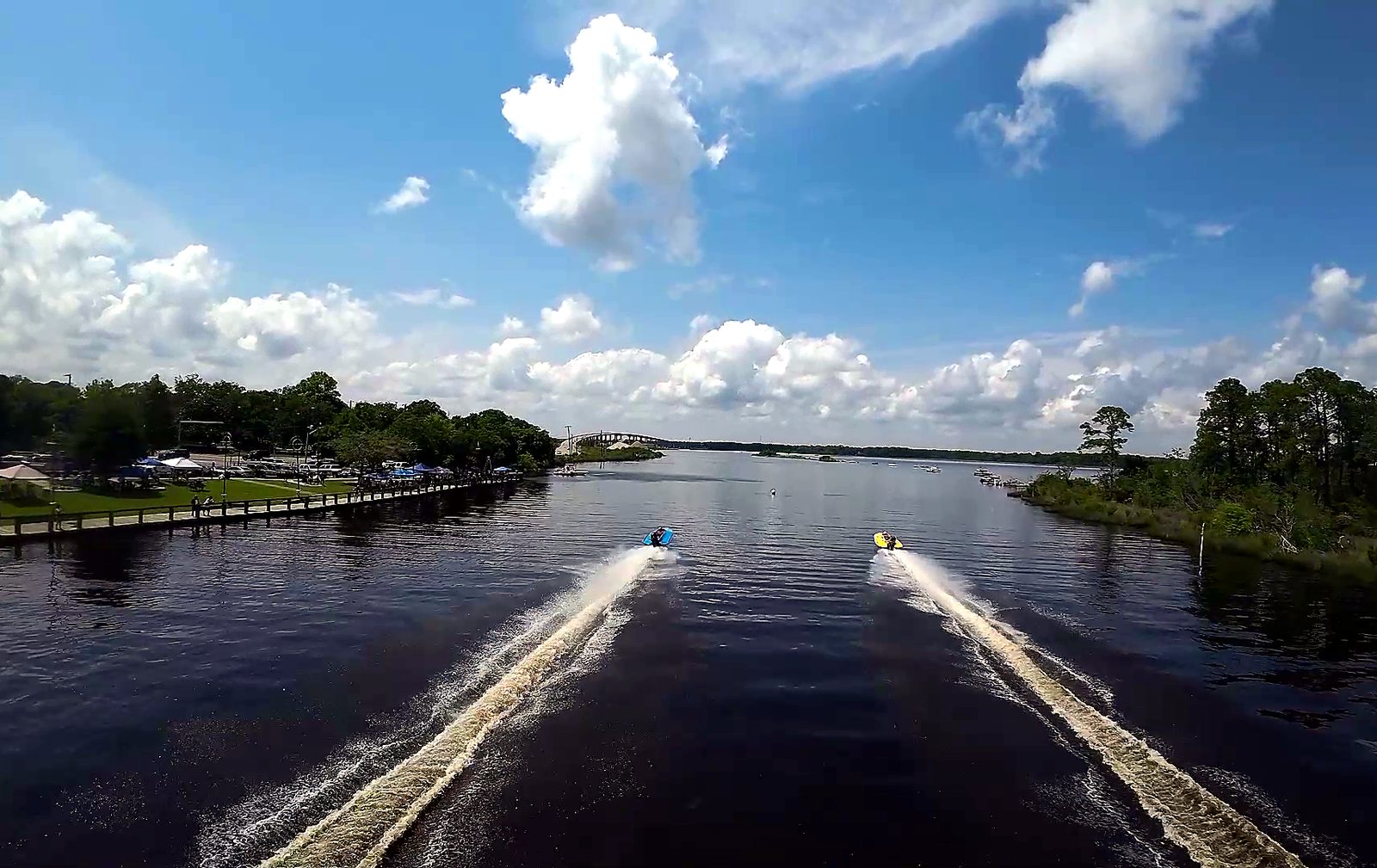 Drag boats streaking away up the river leaving parallel wakes