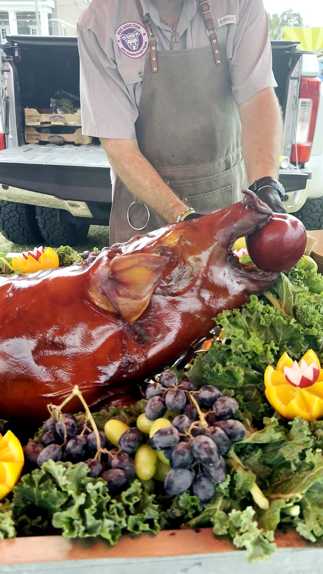 A whole roasted hog presented on a bed of greens and fruit at Smokin' the Sip