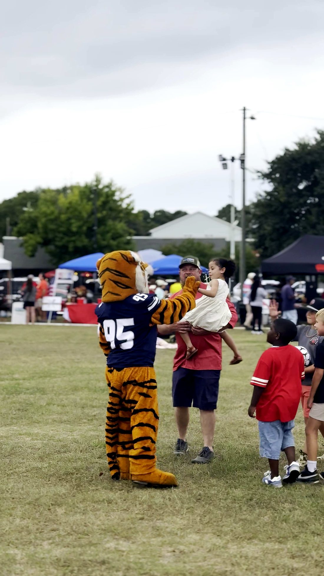 A tiger mascot greeting kids on the festival lawn