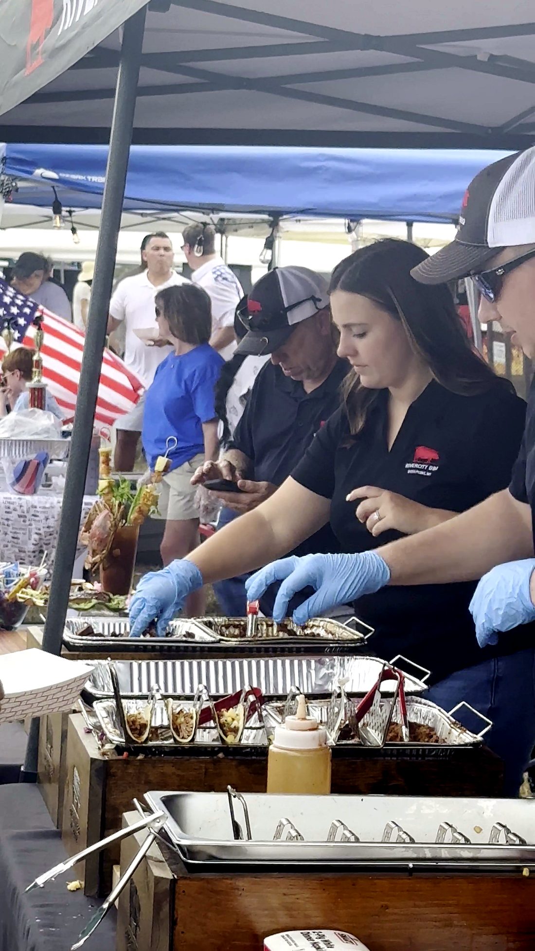 Volunteers serving food from chafing trays under an American flag