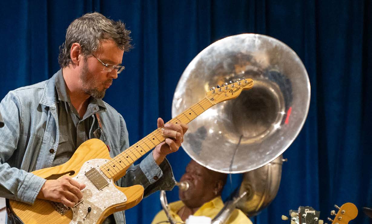 Musicians performing at a Levitt concert, a guitarist beside a sousaphone player